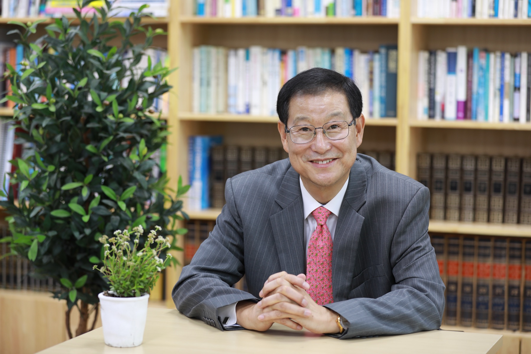 책장 앞에 앉아 미소 짓는 남우택 목사